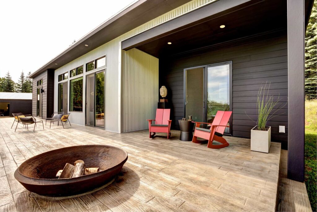 Modern prefab home with firepit, patio seating, and clean architectural lines.