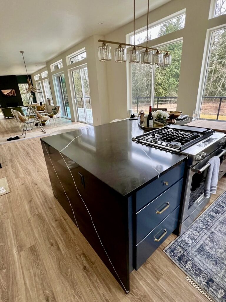 Modern kitchen island with black marble countertop and gold-accented navy drawers.