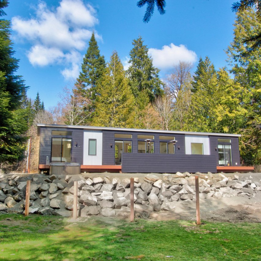 Contemporary modular home with wide front porch and floor-to-ceiling windows.