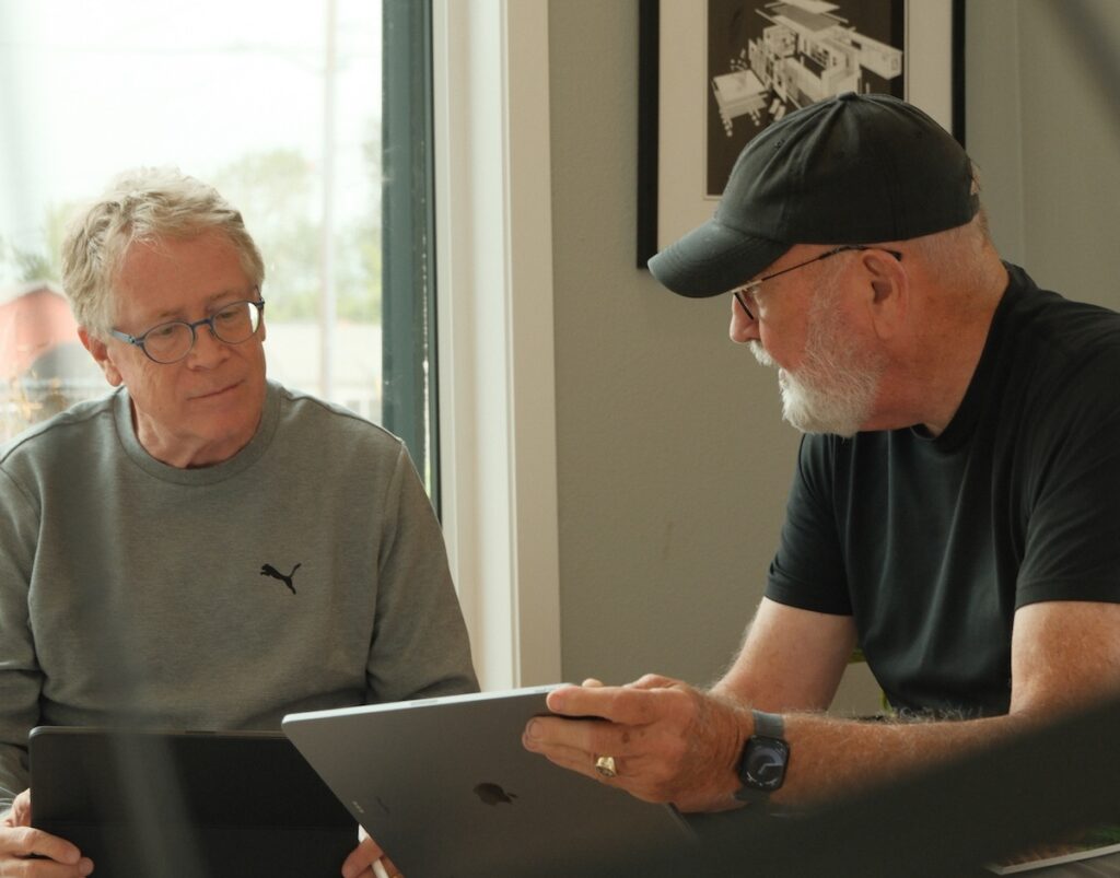 a realistic image of architects discussing or planning the design of their prefab home with the clients that they have in a open area with coffee