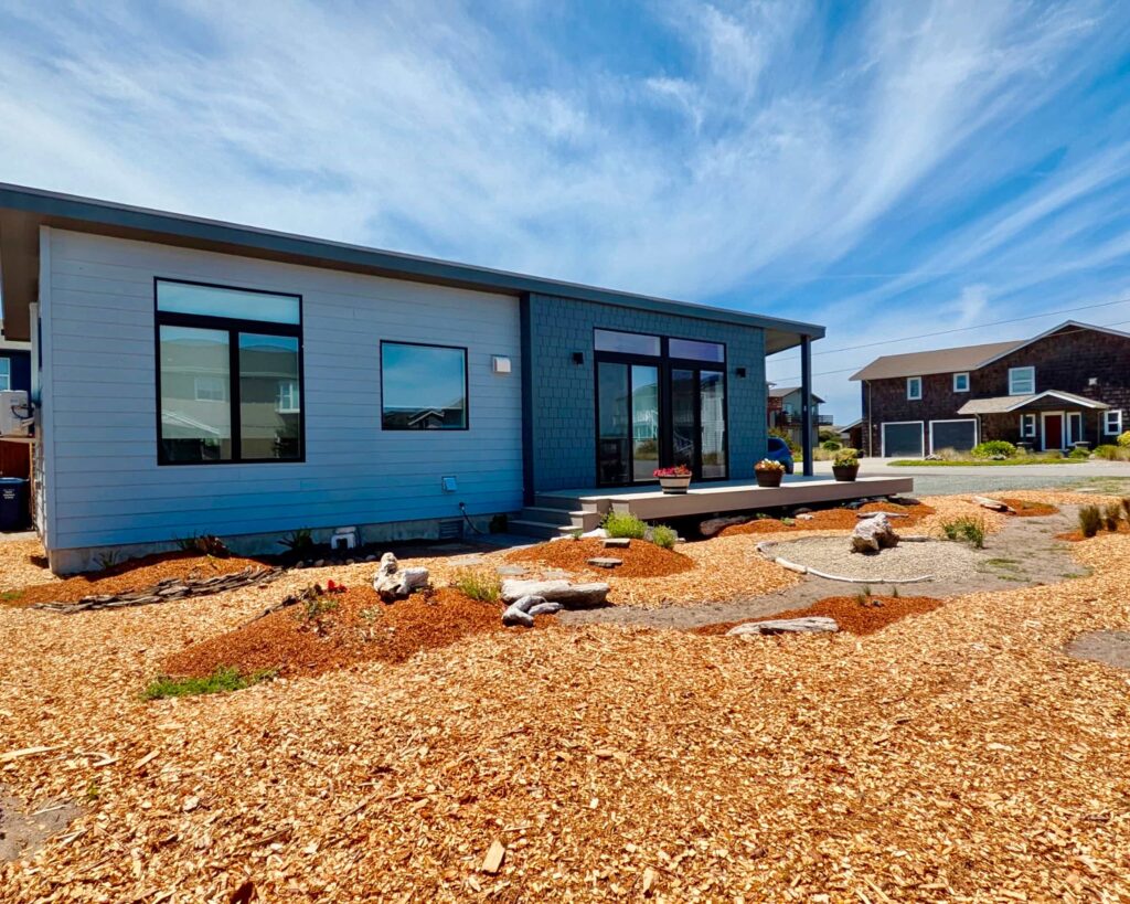 Cauthorn Beach Cottage prefab home with fresh landscaping modern siding and bright blue sky