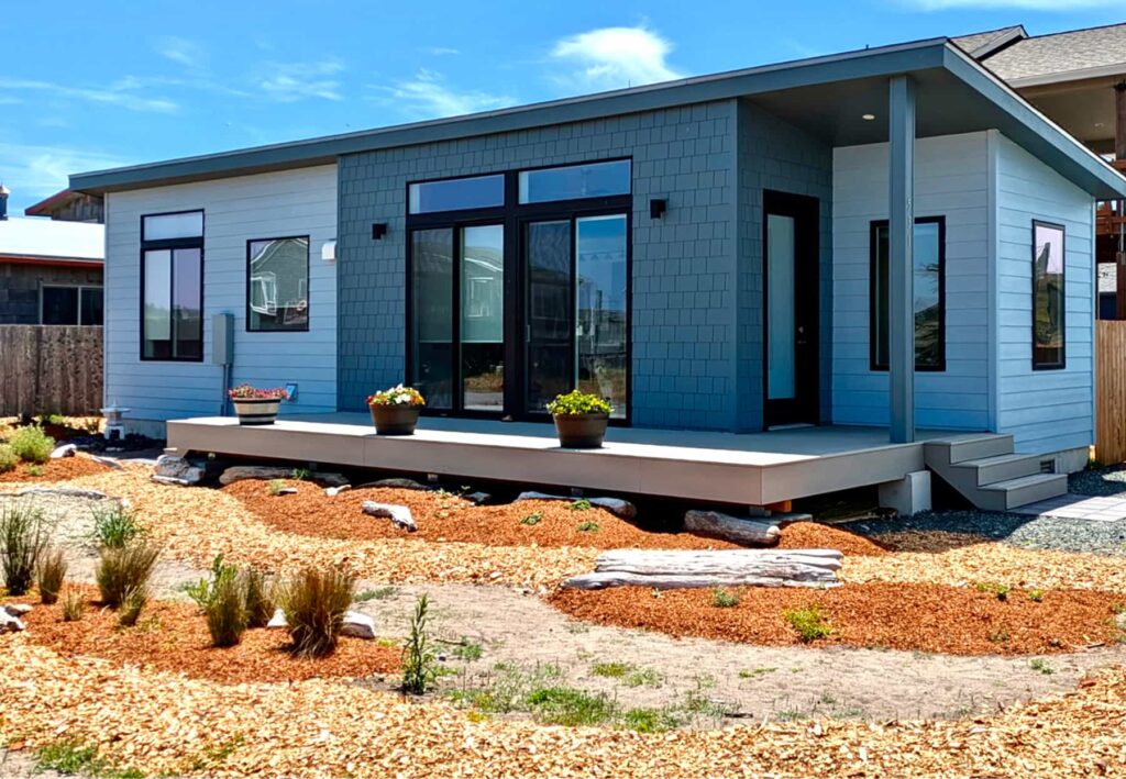 Cauthorn Beach Cottage prefab home with blue siding raised porch and natural front landscaping
