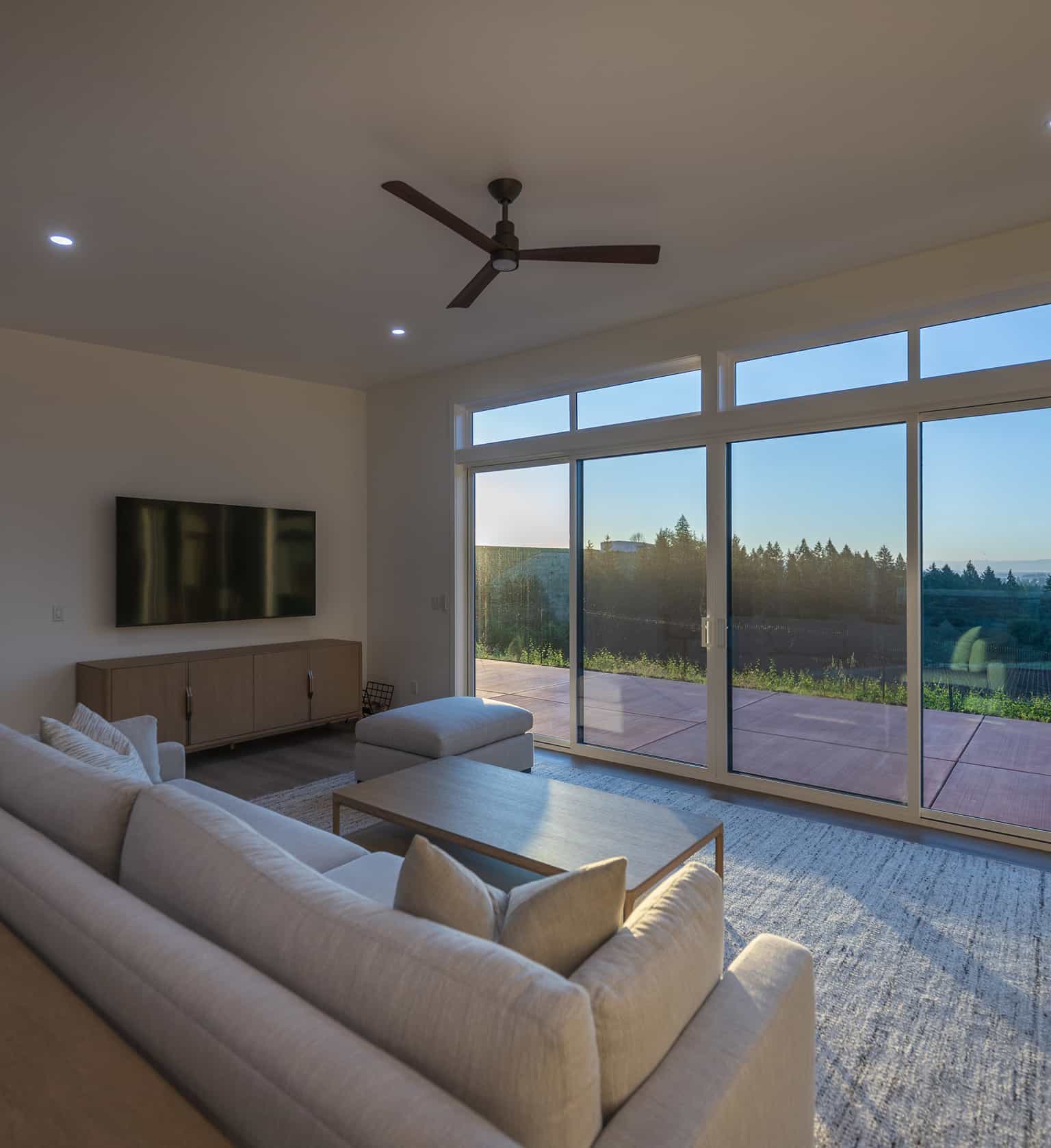 Prefab home living room with large windows serene view neutral furniture and natural evening light