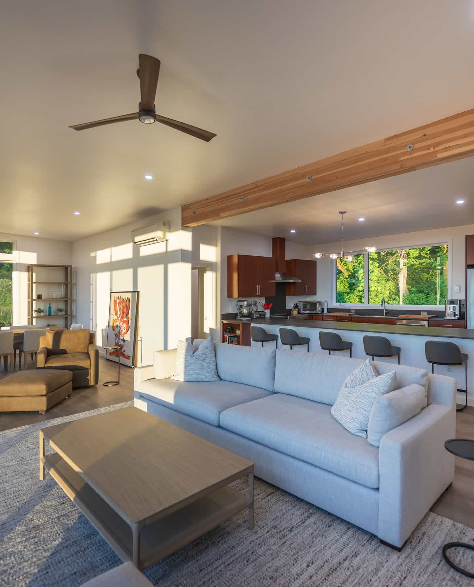 Open concept prefab home interior with modern furniture natural light and wooded views outside