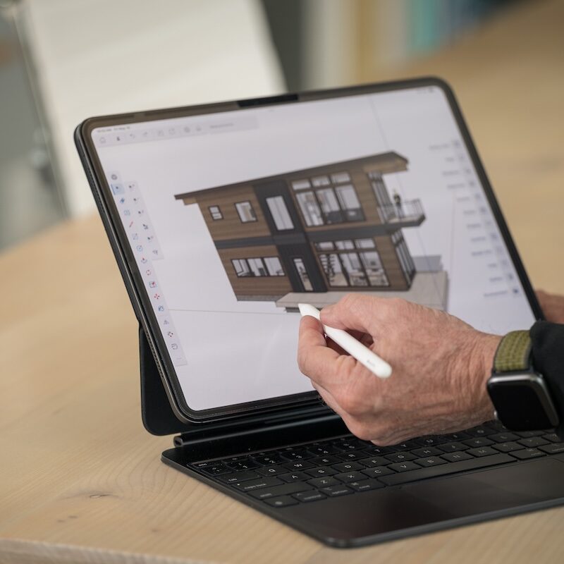 Architect using an iPad to showcase a 3D prefab home design.