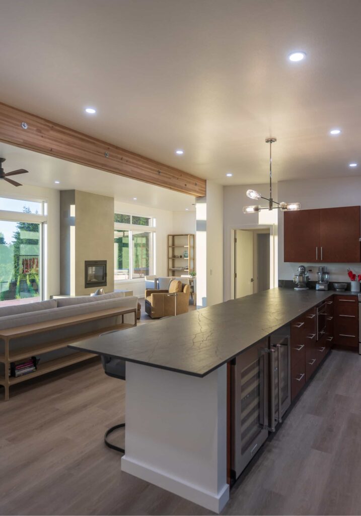 Open-concept kitchen and living area with wood accents, modern lighting, and large windows letting in natural light.