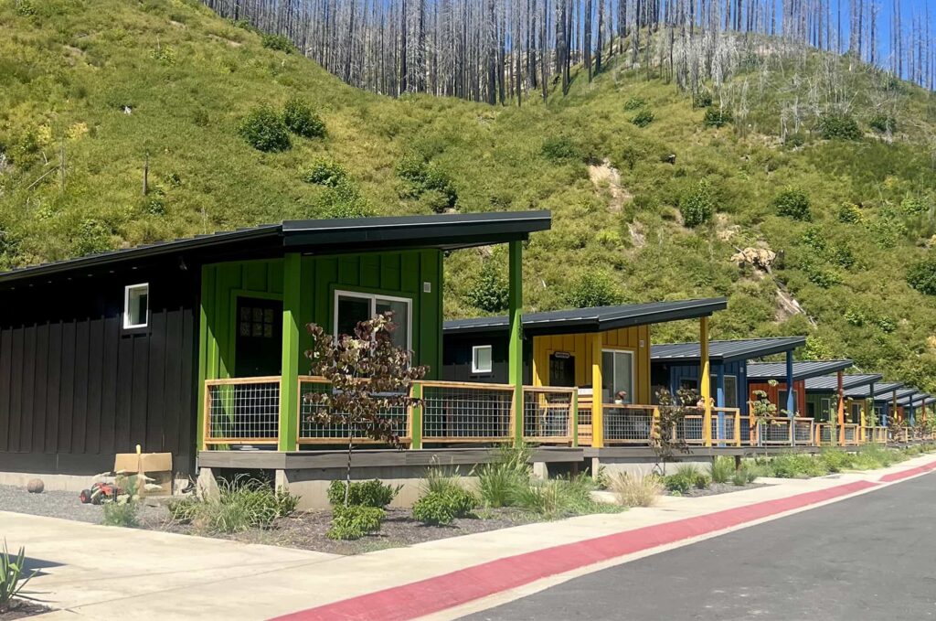 Colorful Ideabox homes lined up against a green hillside